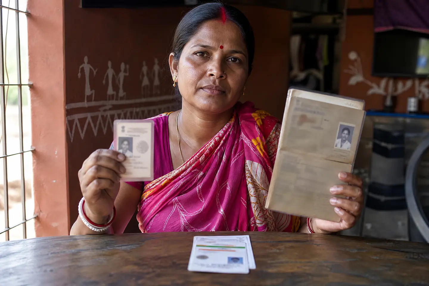 Indian woman holding voter ID, ration card and Aadhaar card as residency proof for the Annapurna Bhandar Scheme